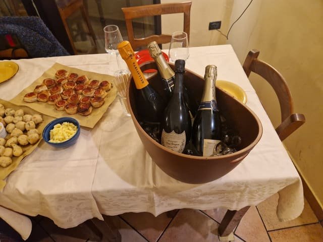 Secchiello di terracotta con quattro bottiglie di spumante e champagne in fresco, su una tavola apparecchiata