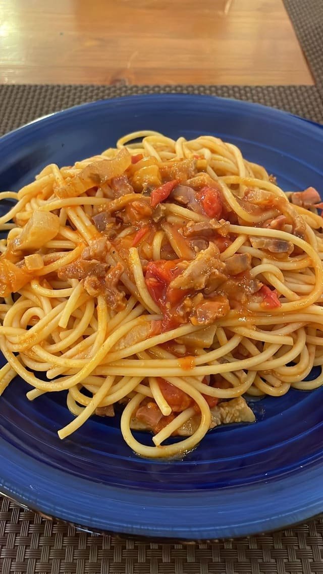 Bucatini all'amatriciana con guanciale su piatto blu