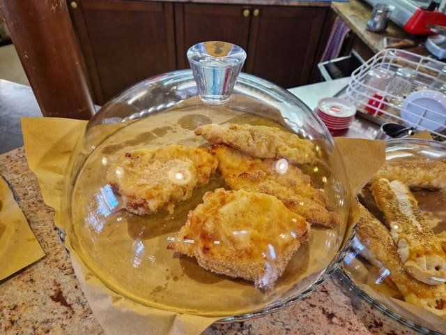 Cotolette impanate sotto la campana di vetro sul bancone della Caffetteria Villa Bousquet