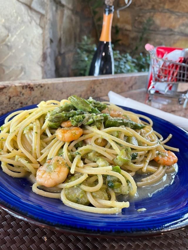 Spaghetti con gamberi e asparagi su un piatto blu